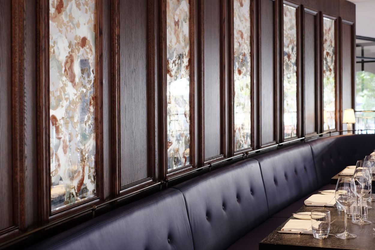 A series of verre églomisé glass panels above banquettes.